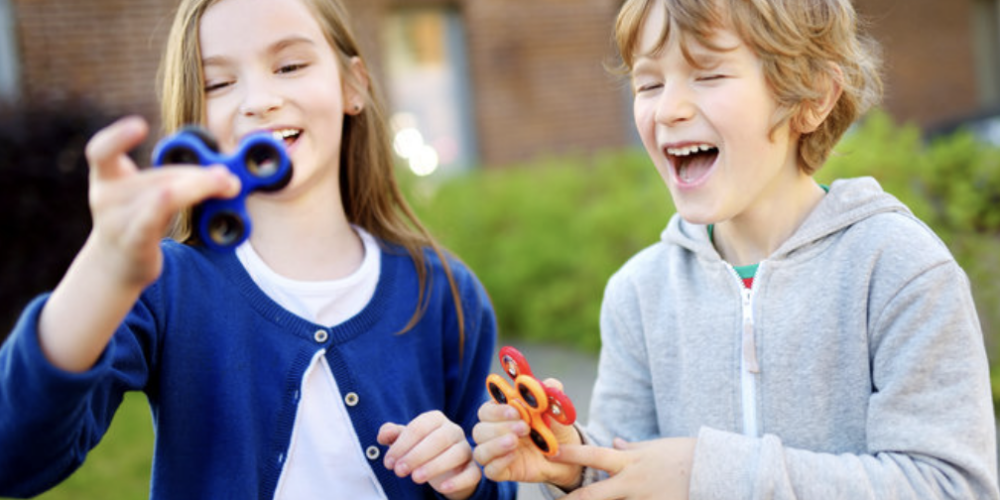 two peers, one with autism, playing with fidget spinners together